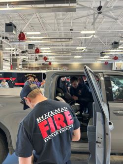 Bozeman Fire firefighters inspecting a car seat in a silver truck.